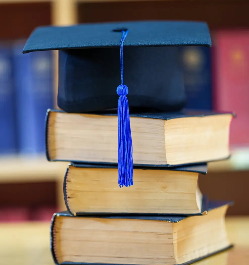 A stack of books with a graduation cap on top.